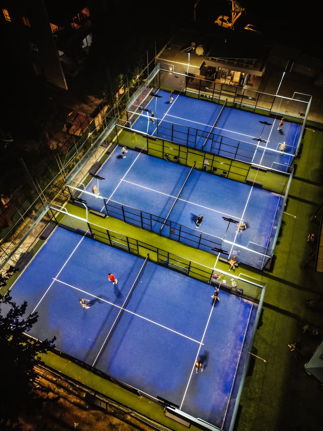 Aerial drone view of the PadelPro courts at night under the lights